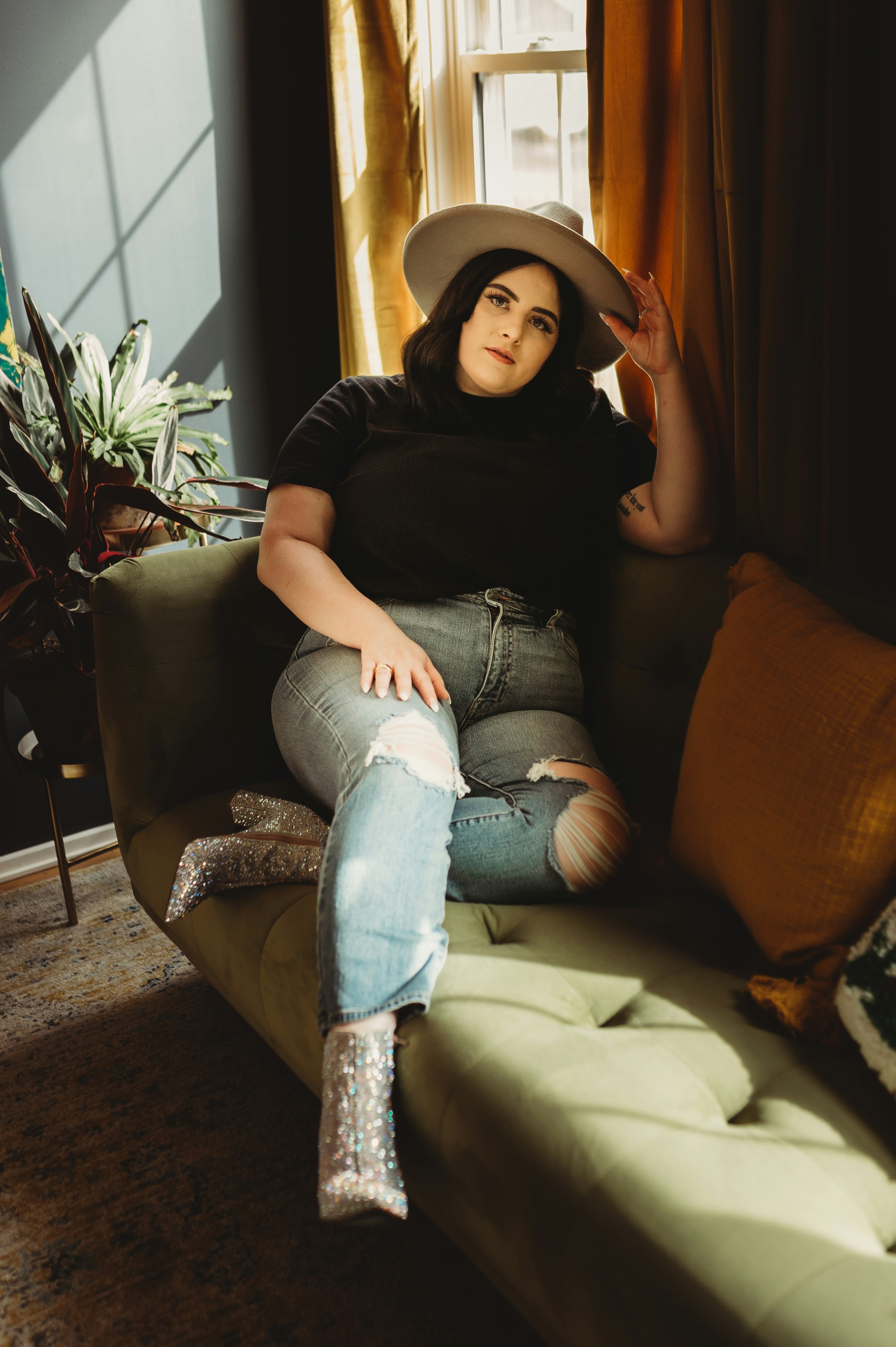 woman in black crew neck t-shirt and blue denim jeans sitting on brown sofa